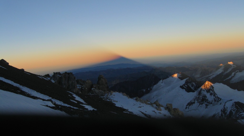 The rising sun just touches the tops of the mountains below and makes Aconcagua cast a huge shadow to the West.